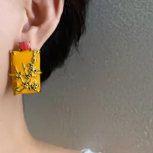 Detailed macro view of New Chinese style yellow enamel earring with golden plum motif on model