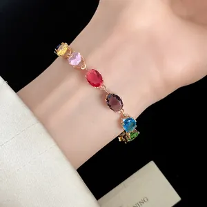Gros plan détaillé d'un bracelet vintage doré avec zircons ovales multicolores au poignet.