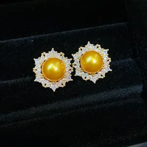 Close-up of golden pearl stud earrings with sparkling zircon halo setting