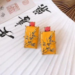Macro detail of New Chinese style yellow enamel earrings with golden plum blossom branches