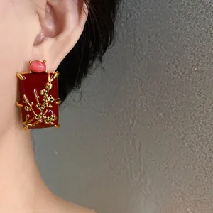 Macro view of New Chinese style red enamel earring with gold plum blossom pattern