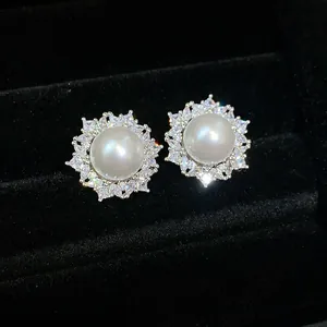 Close-up of elegant pearl earrings with sparkling zircon sunburst halo in a black velvet box