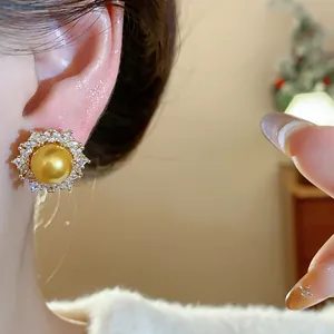Detailed close-up of elegant gold pearl stud earrings with a sparkling zircon halo worn on ear