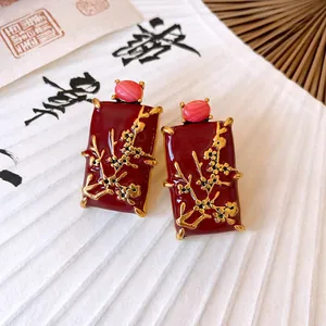 Close-up of New Chinese style red enamel earrings with gold plum blossom pattern