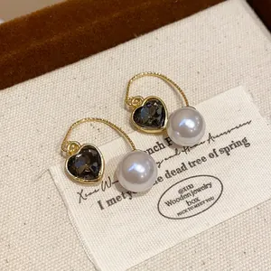 Macro detail of French vintage gold heart earrings with grey crystal and white pearl