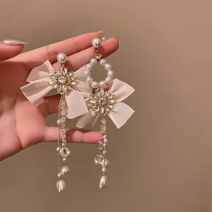 Elegant asymmetric shimmering crystal and pearl tassel earrings with beige ribbon bows