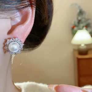 Detail showing elegant French style pearl and zircon stud earrings worn on a model ear