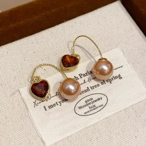 Elegant close-up of French vintage heart-shaped red gem and pink pearl drop hook earrings