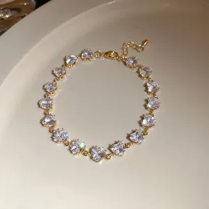 Détail d'un bracelet vintage doré avec des pierres en zircon en forme de cœur sur une assiette.