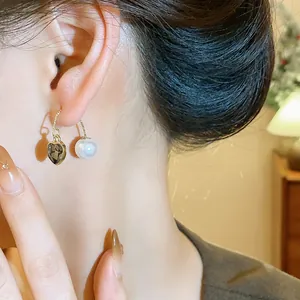 Close-up of elegant French vintage earrings with heart gemstone and pearl on model.