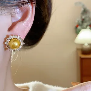 Elegant French style gold pearl earring with shimmering zircon halo worn on ear