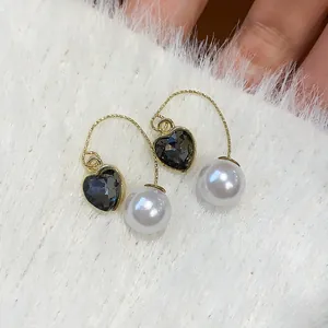 Close-up of French vintage heart-shaped crystal and pearl drop earrings on white fur