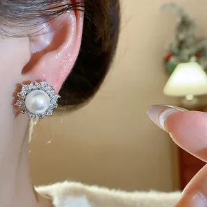 Close-up view of elegant French style pearl earrings with zircon halo worn on woman ear.