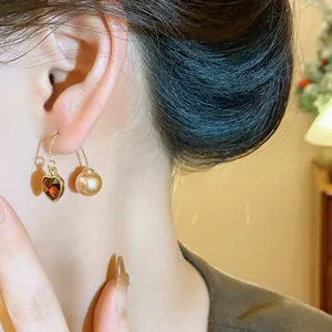 Close-up view of French retro gold earrings featuring an amber heart and pearl detail