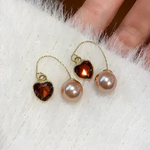 Close-up of French vintage heart-shaped red stone and pink pearl earrings on white fur