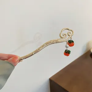 Elegant close-up of a Chinese-style gold hair pin with cloud motif and persimmon charms