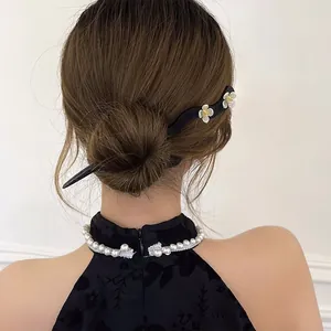 Detail showing a black floral hairpin styled in a traditional Chinese bun with qipao