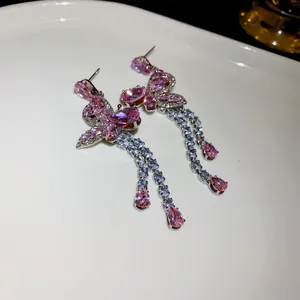 Detailed macro view of pink zircon butterfly tassel earrings with silver needle