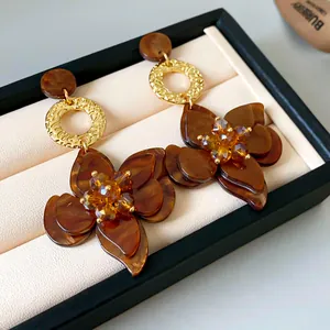 Detail of amber flower drop earrings with golden textured circle on jewelry tray.