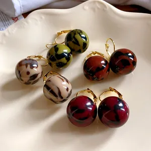 Primo piano di orecchini a palla in resina leopardata retrò in vari colori autunnali.