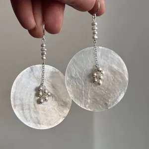 Dettaglio di orecchini boho in madreperla con delicati nappe di perle stile vintage.