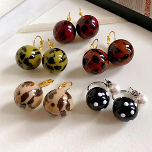 Dettaglio di vari orecchini a sfera in resina con motivi leopardati e a pois.