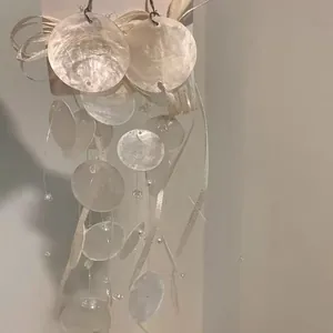 Dettaglio ravvicinato di orecchini a nappine in conchiglia bianca stile resort elegante
