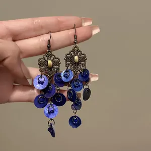 Dettaglio di orecchini boho con nappe di conchiglia blu e finiture in bronzo vintage