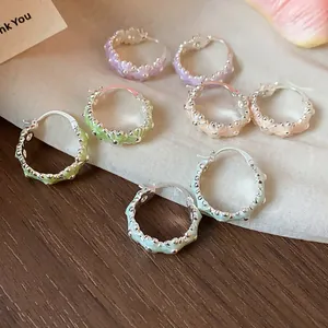 Close-up of colorful pastel floral drip oil hoop earrings on a wooden background.