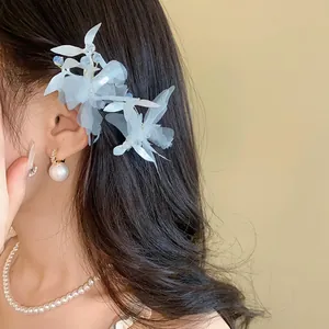 Vue détaillée d'une barrette à cheveux fleur et papillon bleue sur une chevelure sombre.