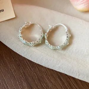 Detailed close-up of mint green enamel flower hoop earrings with silver-toned finish.