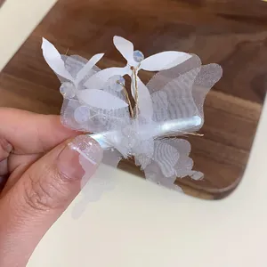 Vue détaillée d'une pince à cheveux papillon en maille blanche avec perles de cristal