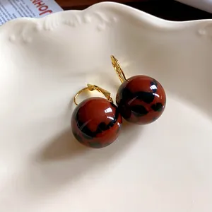 Primo piano di orecchini a sfera in resina leopardata retrò con ganci dorati.