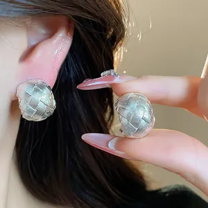 Dettaglio ravvicinato di orecchini a clip intrecciati argento che mostrano la lavorazione