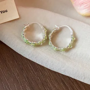 Detailed macro shot of elegant green enamel flower hoop earrings in silver finish