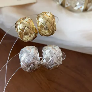 Dettaglio degli orecchini a clip intrecciati placcati in oro 18k nei colori oro e argento.
