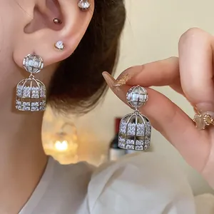 Vista detallada de elegantes pendientes de jaula de plata con circón y perlas