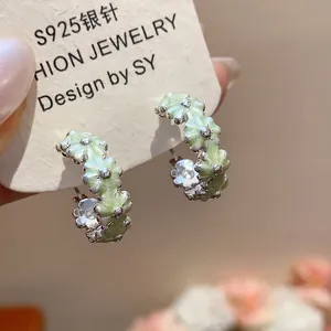 Macro detail view of elegant light green enamel flower hoop earrings with silver finish