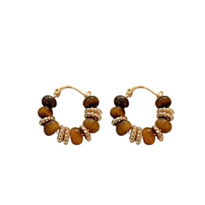 Gold plated hoop earrings with tiger eye beads and textured spacers on white background