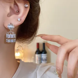 Primer plano detallado de un elegante pendiente de plata con forma de jaula y circonitas