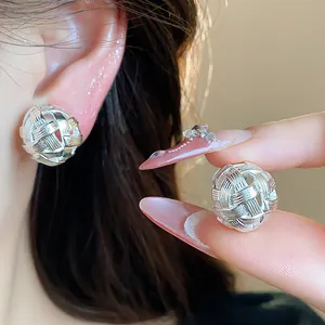 Primo piano dettagliato di orecchini a sfera traforati intrecciati in argento lucido.
