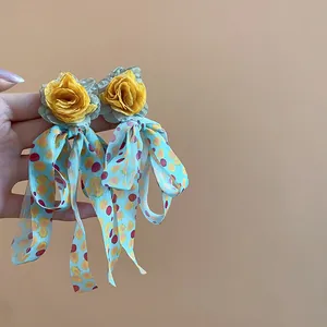 Detailed view of handmade flower drop earrings featuring blue polka dot silk ribbons