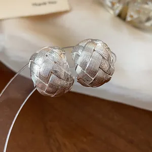 Dettaglio macro di orecchini a clip argentati con trama intrecciata senza buco