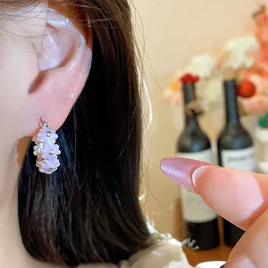 Close-up of sweet pink enamel flower hoop earrings worn on ear for a delicate look.