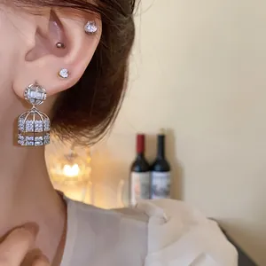 Elegantes pendientes de jaula de plata con circonitas mostrados en una modelo chic.