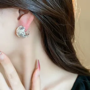 Primo piano di un elegante orecchino a clip intrecciato e traforato argento da donna.
