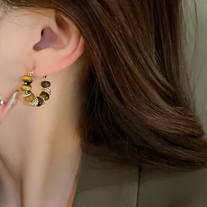 Close-up view of elegant gold plated hoop earrings featuring natural tiger eye stone beads