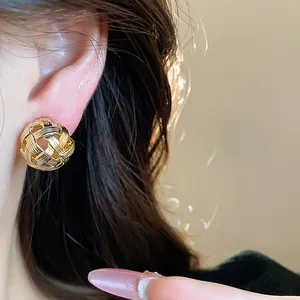 Dettaglio ravvicinato di orecchini a clip intrecciati placcati in oro 18 carati sull'orecchio