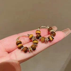 Close-up detail of gold-plated hoop earrings with tiger eye stone beads and gold spacers
