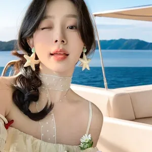 Asian model wearing oversized golden starfish earrings on a sunny yacht holiday